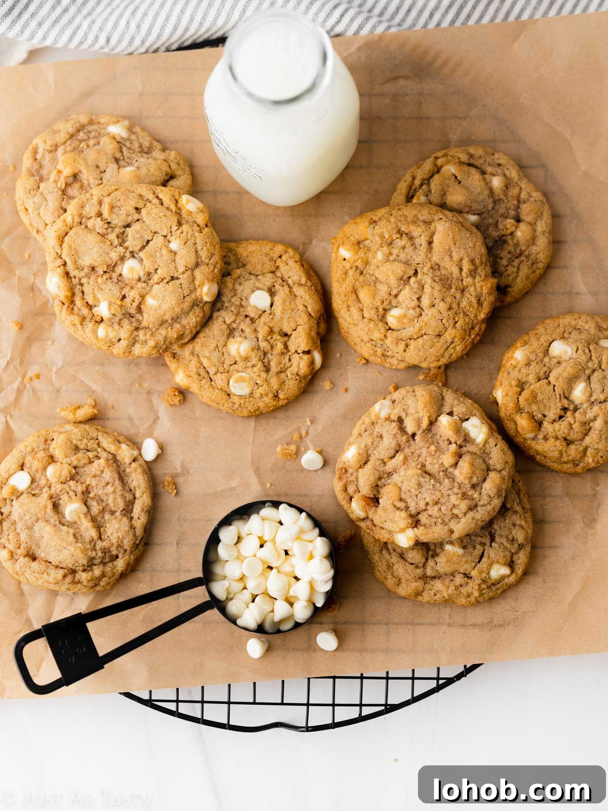 Chewy Apple Cinnamon Cookie Recipe for Soft, Spiced Treats 6 Apple cinnamon cookies on brown parchment with a glass of milk and white chocolate chips.