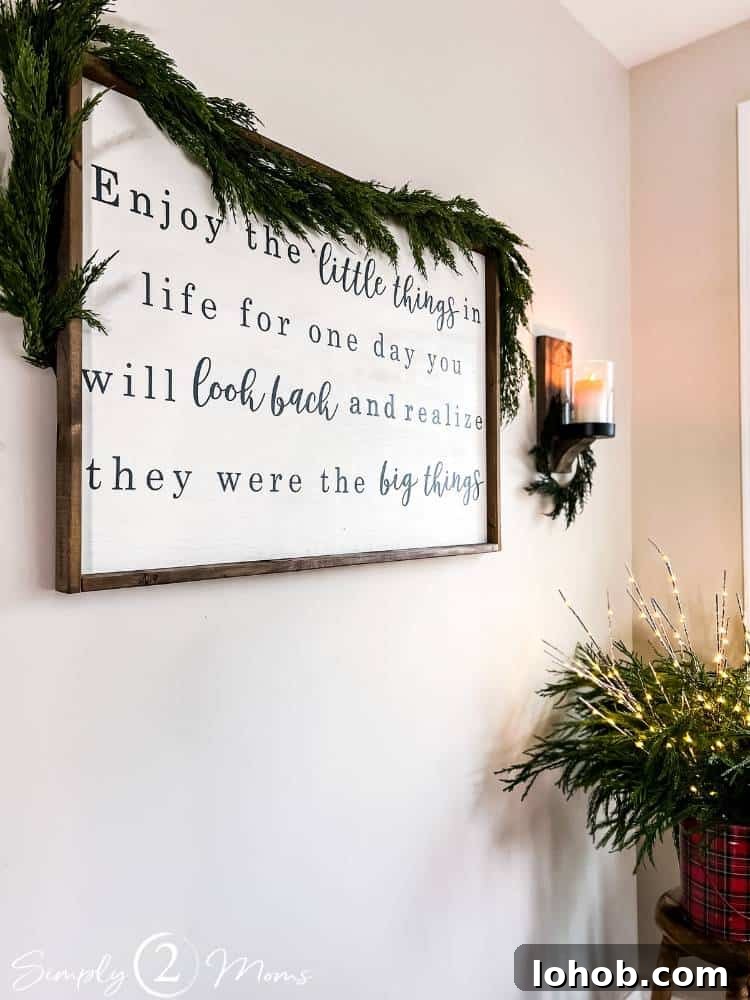 wall decor with garland over top of sign and greenery in corner