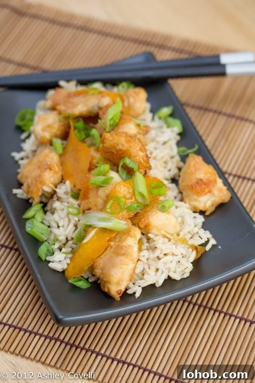 Crispy Orange Chicken with Scallions and Garlic Sauce 2 Orange chicken over rice garnished with green onions.