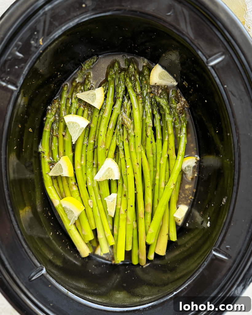overhead shot of cooked close up shot of Slow Cooker Lemon Garlic Asparagus in a black slow cooker