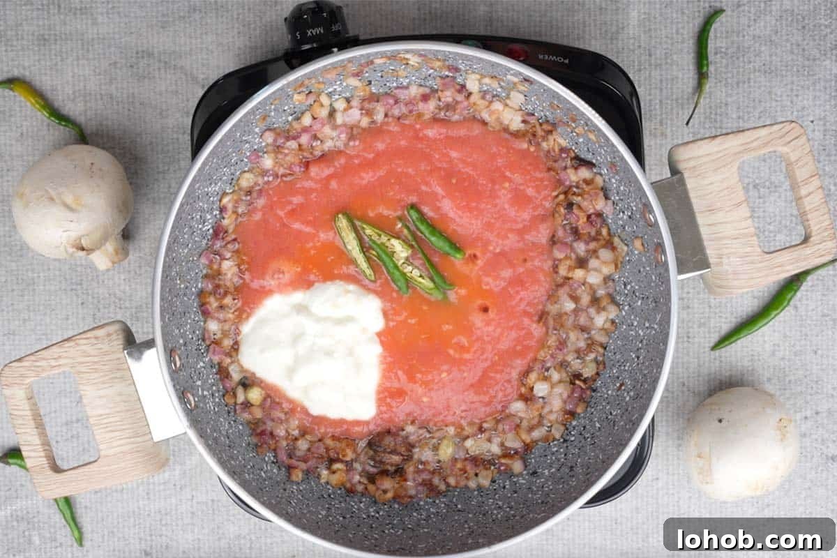 Tomato, yogurt and green chilies added to the pan.