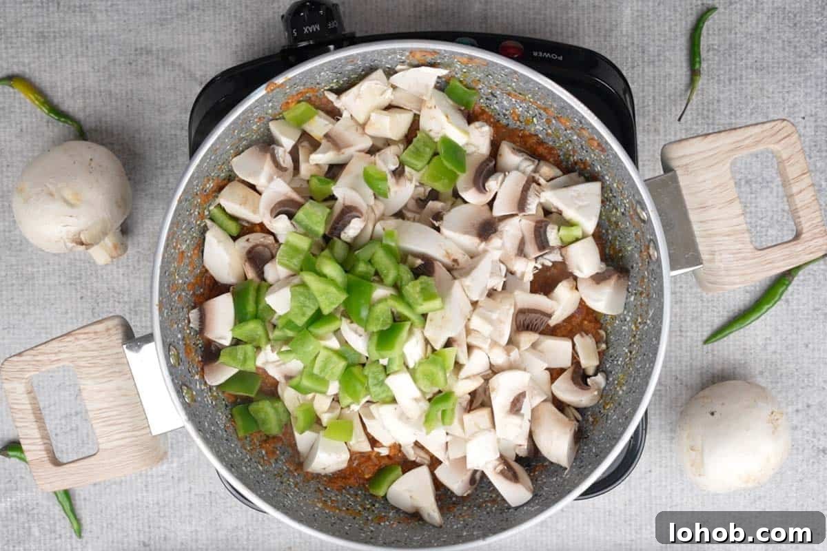 Mushrooms and bell pepper added to the pan.