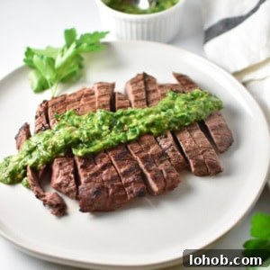 Grilled Flank Steak with zesty Chimichurri Sauce 5 Grilled flank steak with a bowl of chimichurri in the back next to a towel