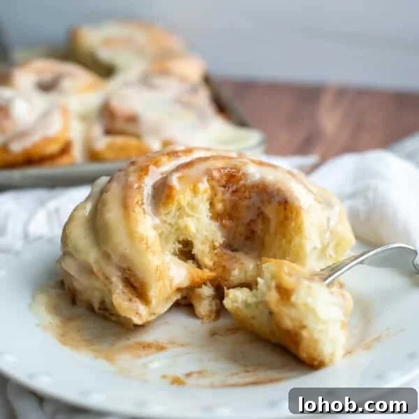 Soft Gooey Cinnamon Rolls Recipe for Perfectly Fluffy Layers 19 Sourdough Cinnamon roll on a plate with the center of the roll on a fork.