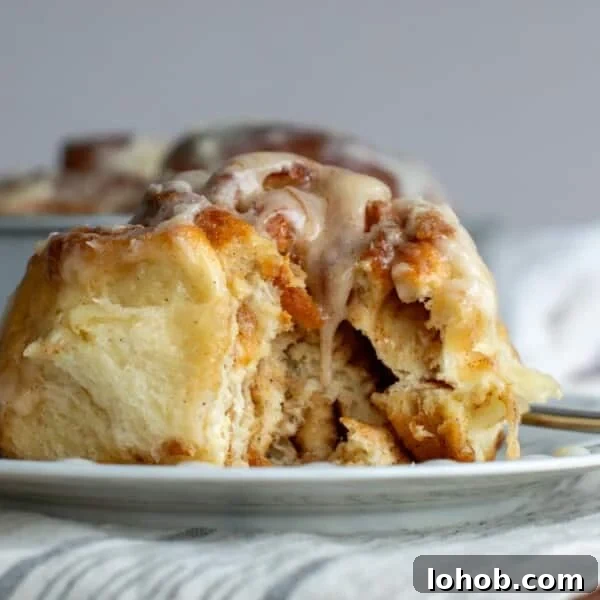Soft Gooey Cinnamon Rolls Recipe for Perfectly Fluffy Layers 20 Sourdough discard cinnamon roll on a plate with a bite taken out of it.