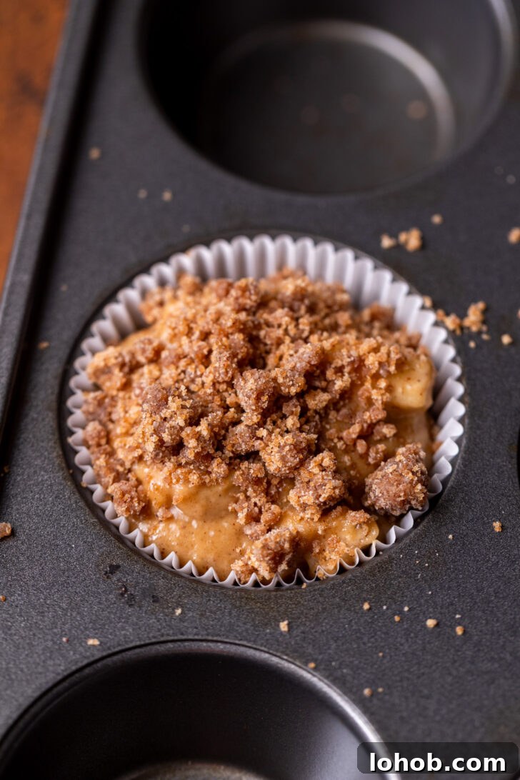 Moist Apple Muffin Recipe with Cinnamon Streusel 8 Crumb topping on top of muffin batter.