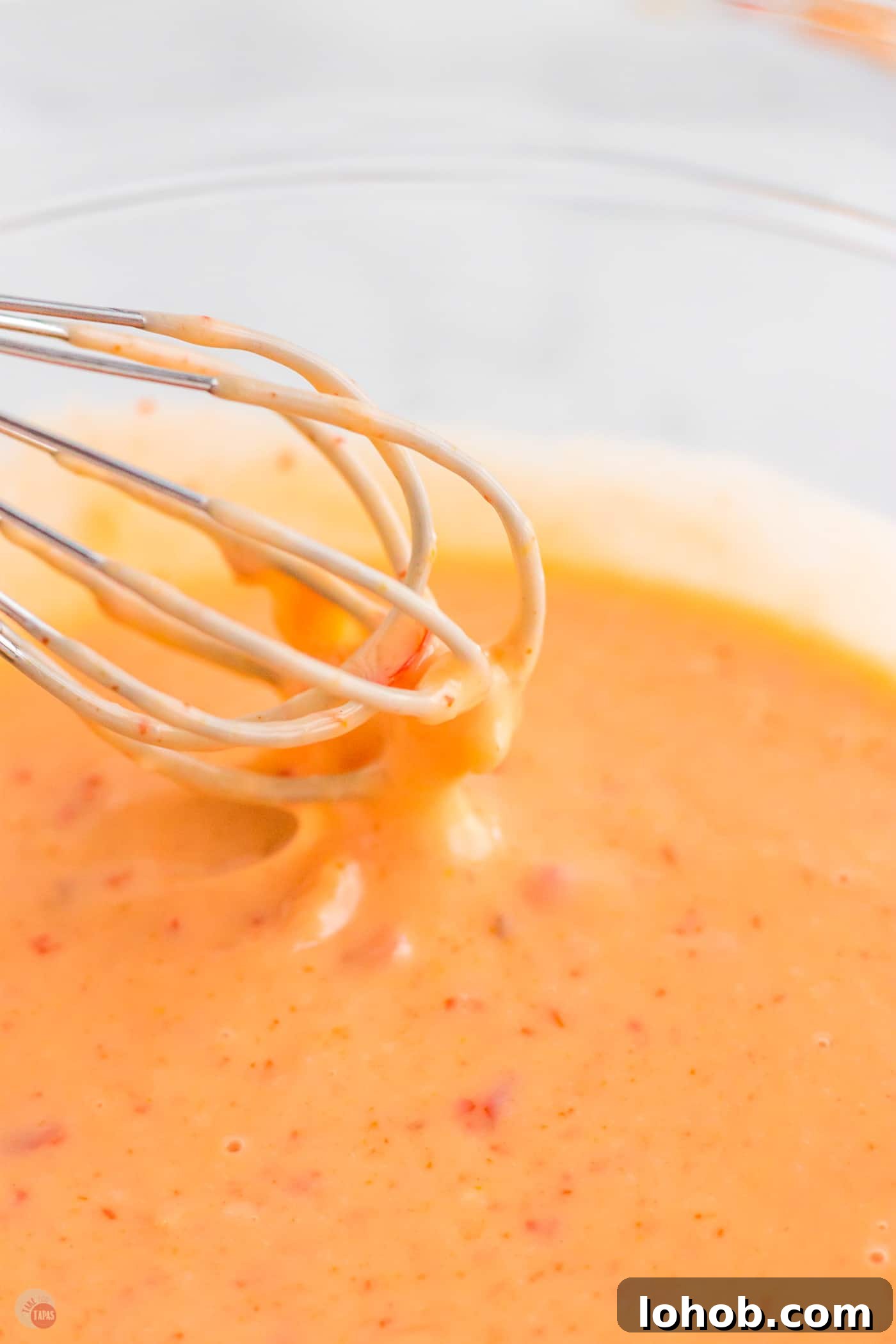 whisk dipping into sauce