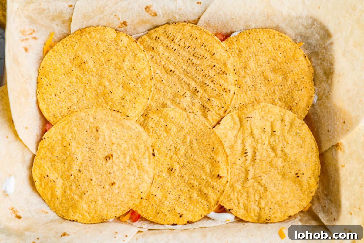 Tostada shells layered on top of the sour cream layer.