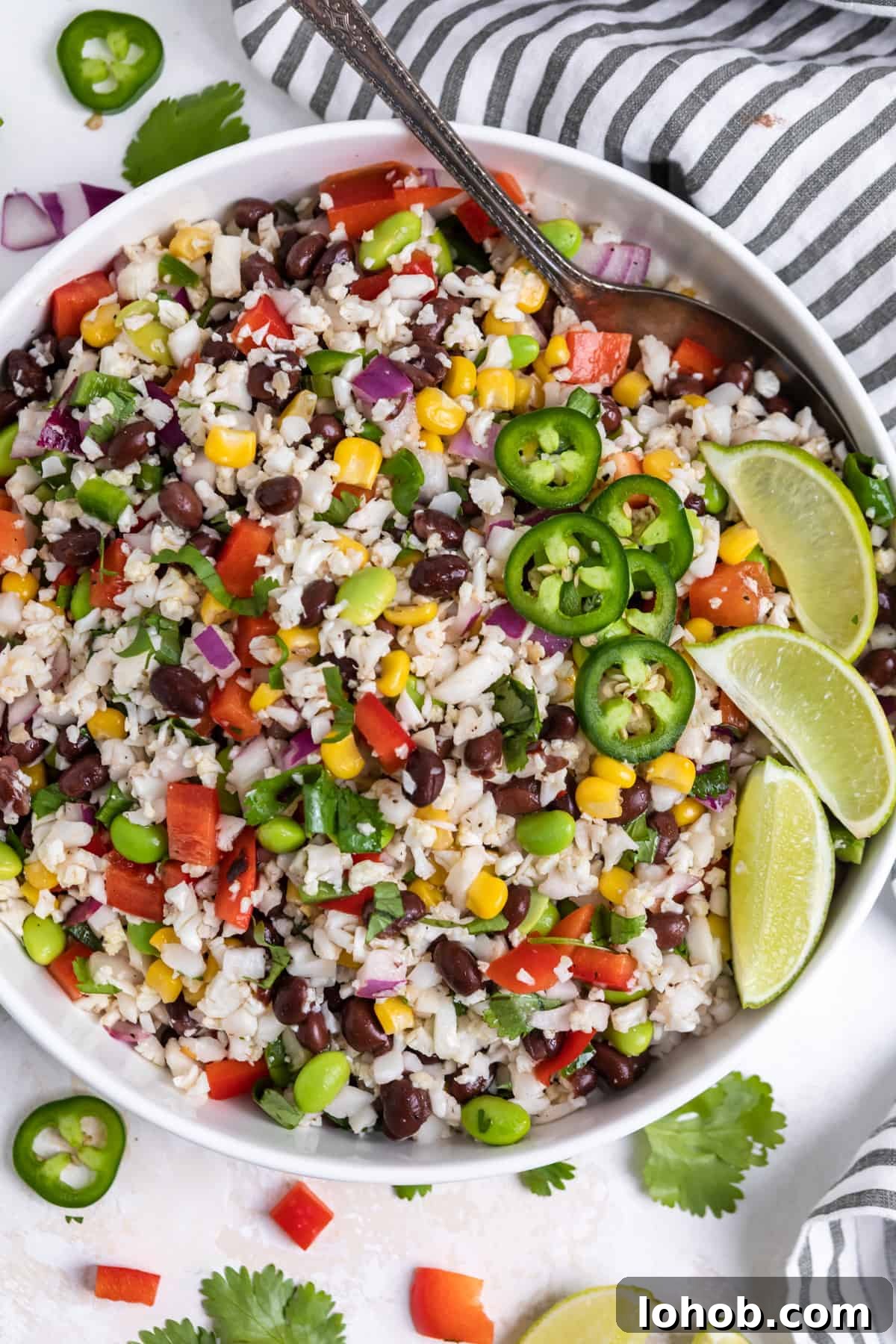 Black Bean & Cauliflower Rice Salad with Lime and Cilantro 2 White salad bowl with cauliflower rice salad with black beans, corn, cilantro and serving spoon.
