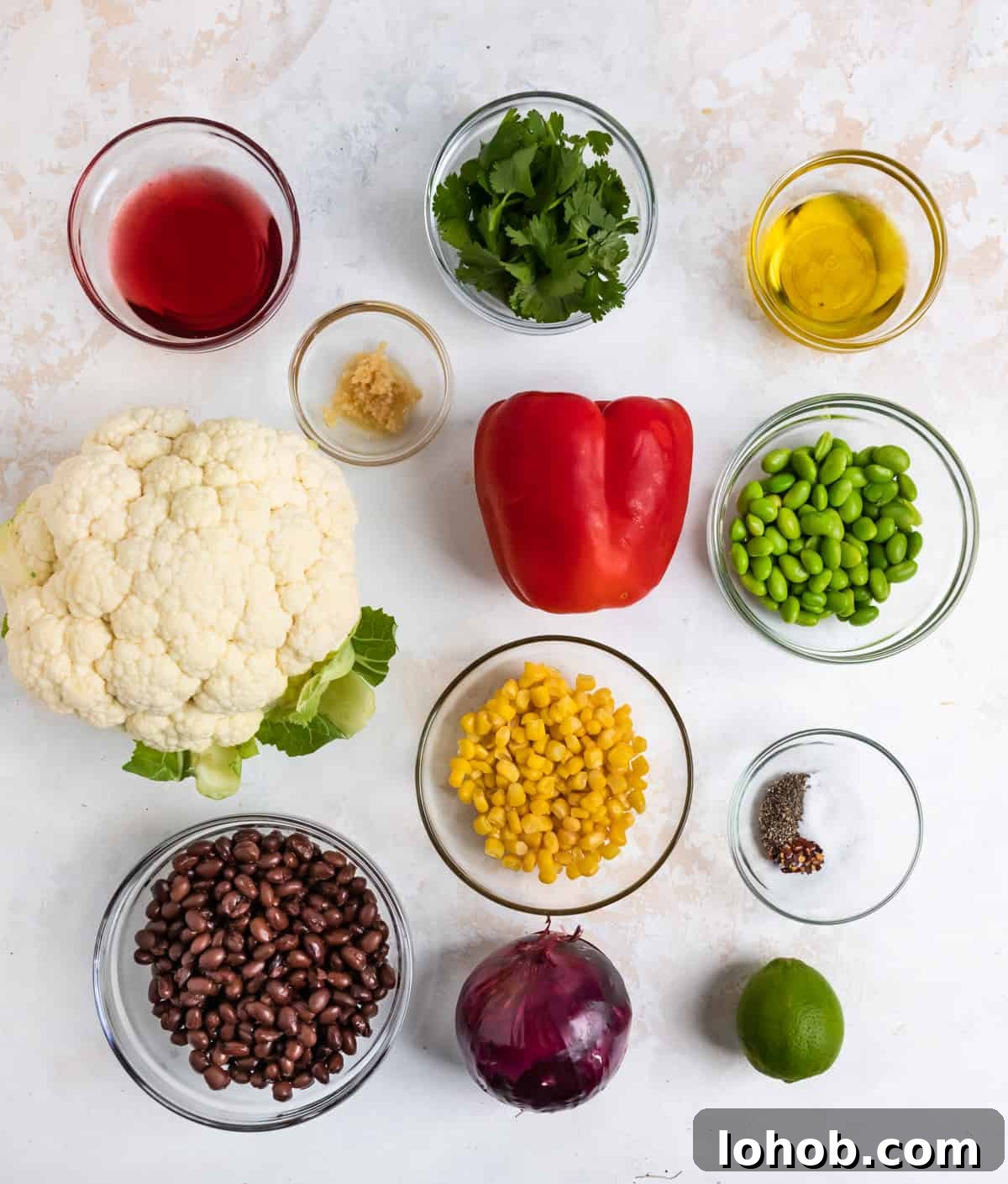 Black Bean & Cauliflower Rice Salad with Lime and Cilantro 3 Cauliflower, corn, black beans, peppers, lime and other ingredients on counter.