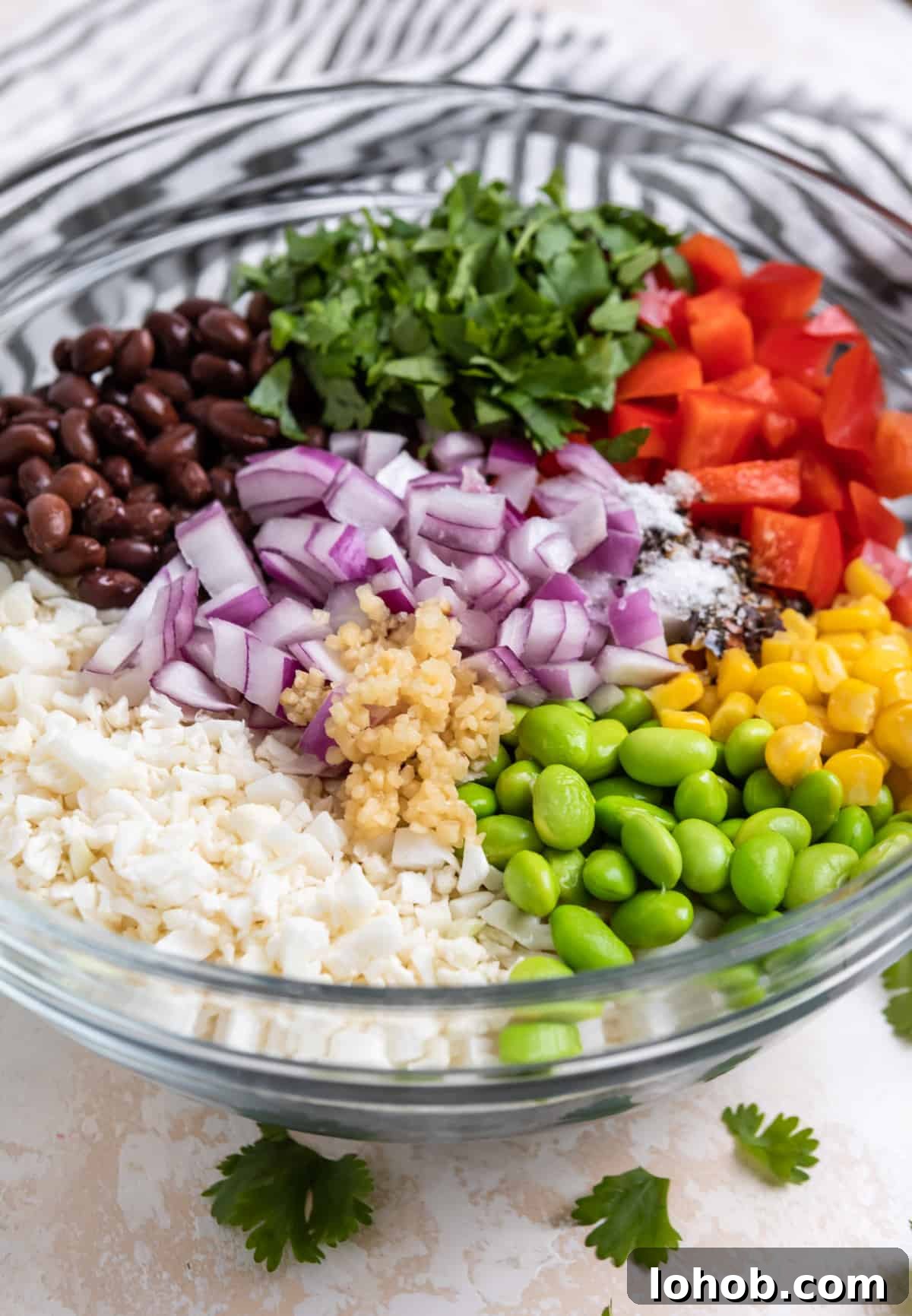 Black Bean & Cauliflower Rice Salad with Lime and Cilantro 4 Glass mixing bowl with cauliflower rice, beans, peppers, corn and other salad ingredients.