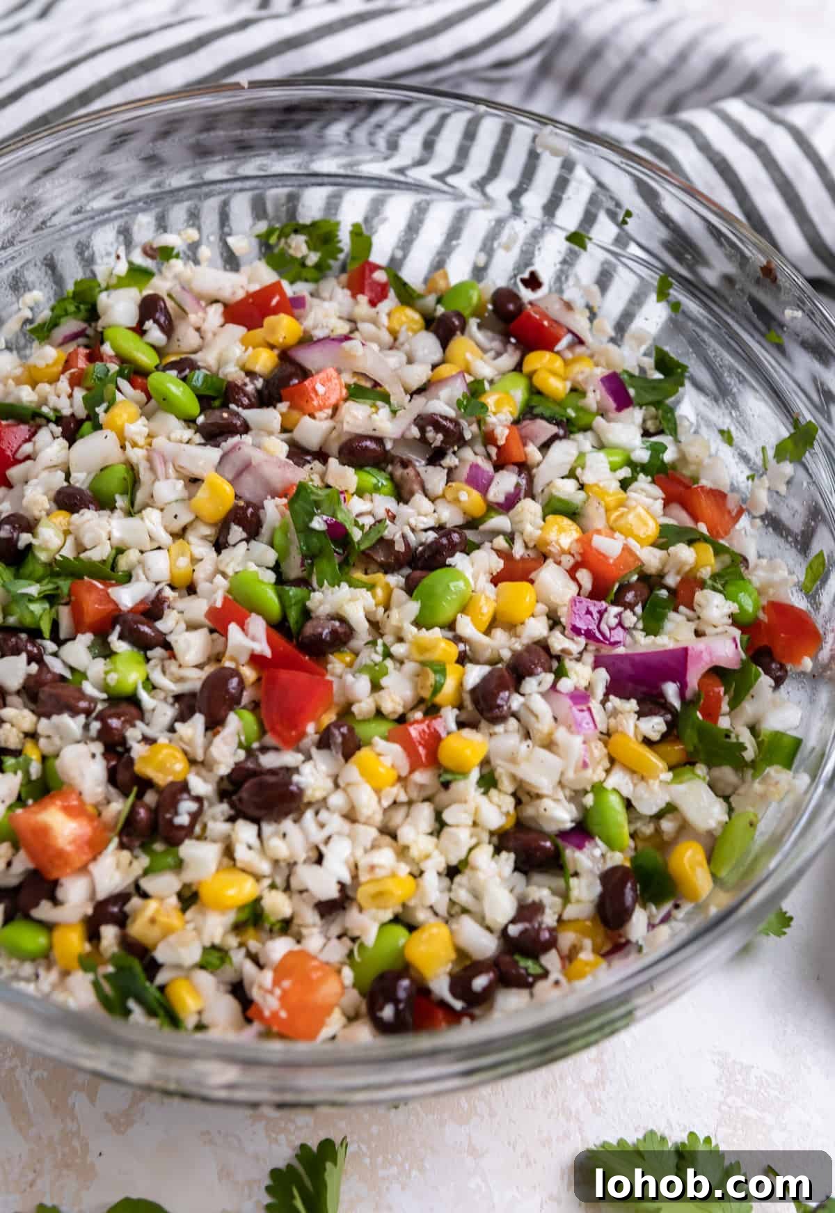 Black Bean & Cauliflower Rice Salad with Lime and Cilantro 5 Tossed cauliflower black bean salad in glass bowl.