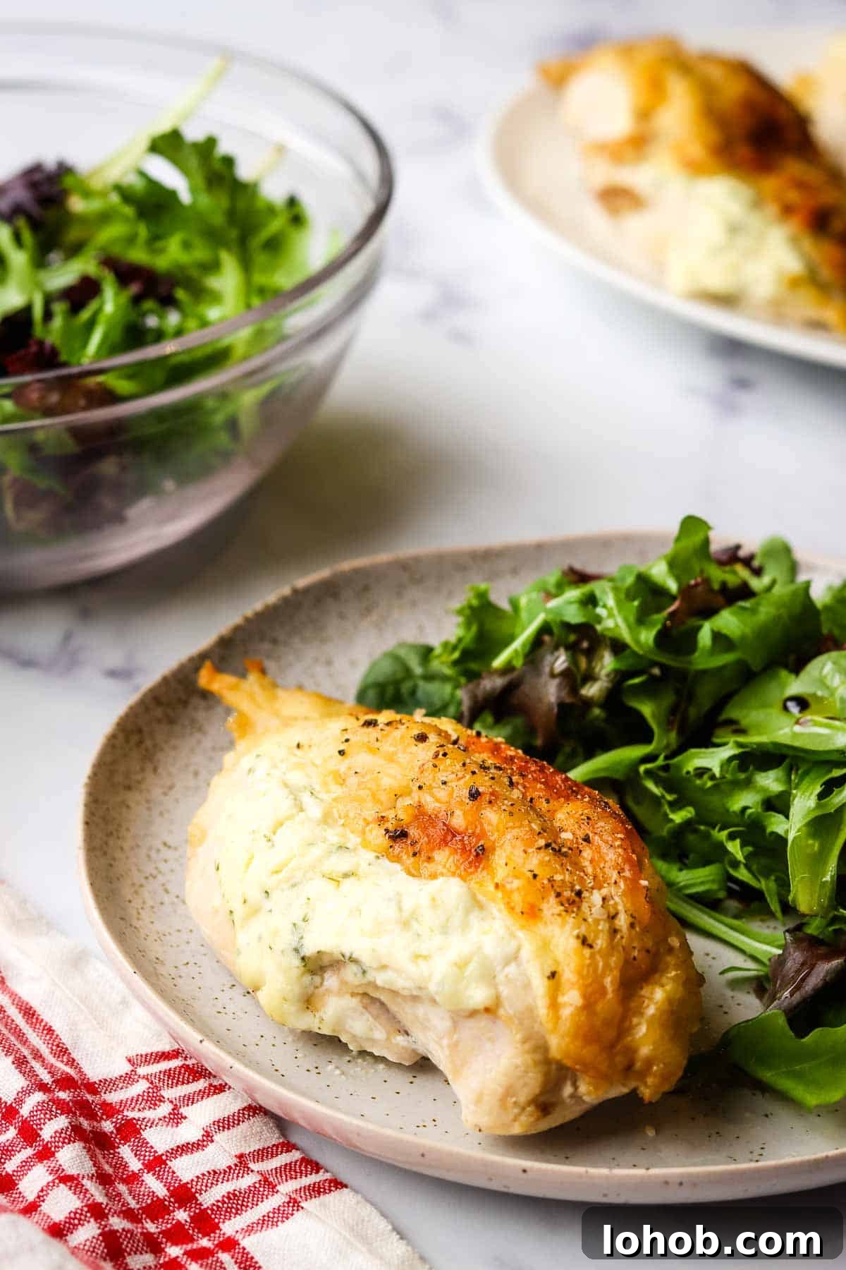 Creamy Boursin-Stuffed Chicken Breast Recipe 2 boursin chicken breast plated on a dish with a side salad.