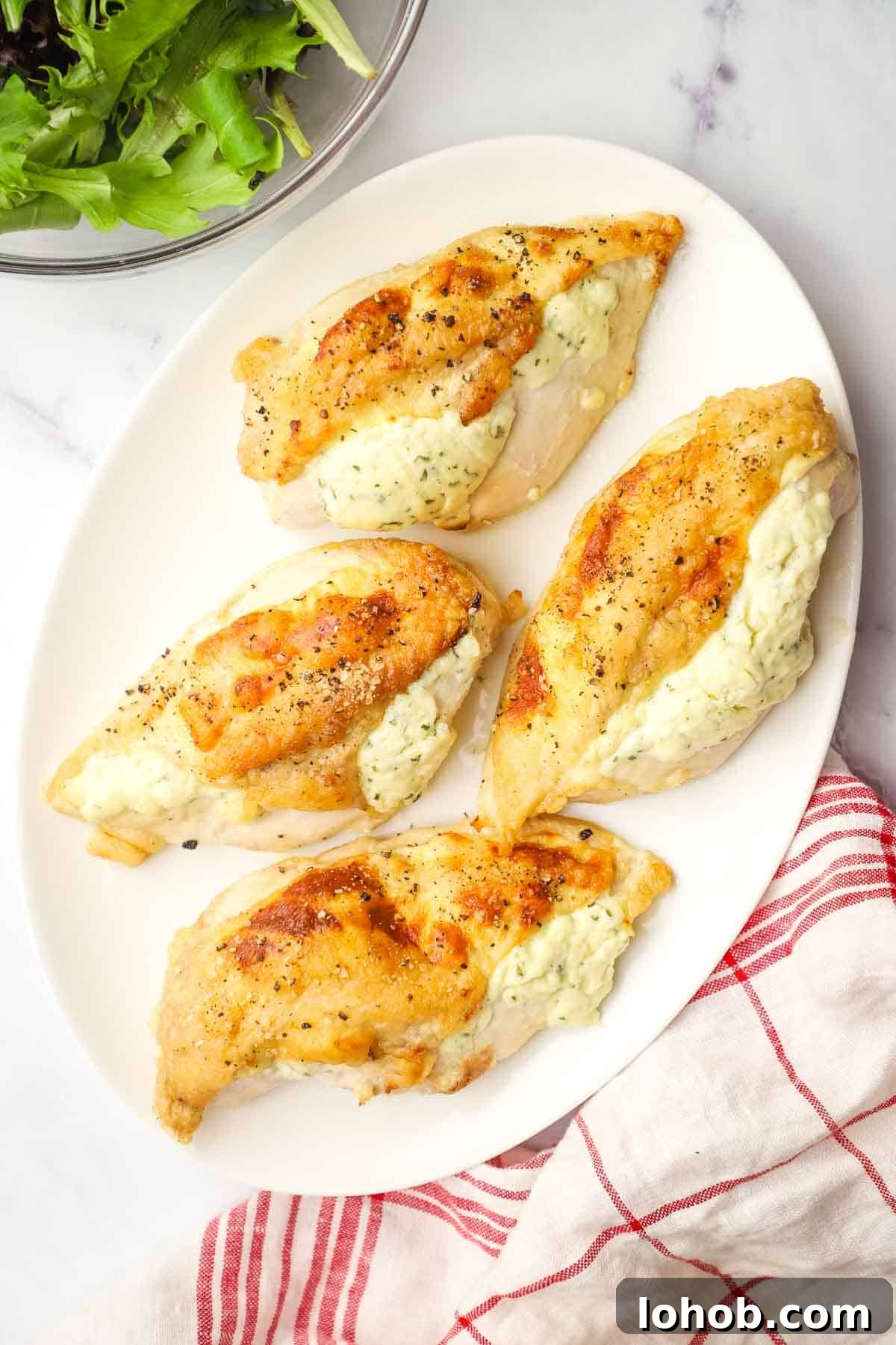 Creamy Boursin-Stuffed Chicken Breast Recipe 4 Four Boursin stuffed-chicken breasts on a white oval platter.