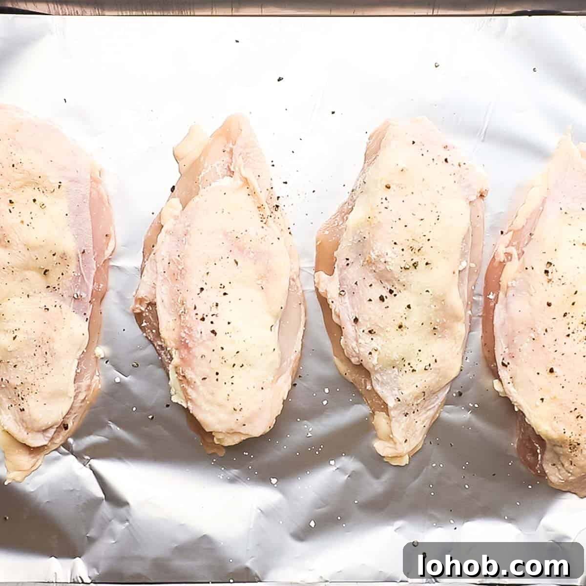 Creamy Boursin-Stuffed Chicken Breast Recipe 8 stuffed and seasoned chicken breasts placed on a baking sheet lined with aluminium