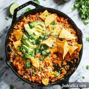 One pot Mexican rice in a skillet with avocado and tortilla chips.