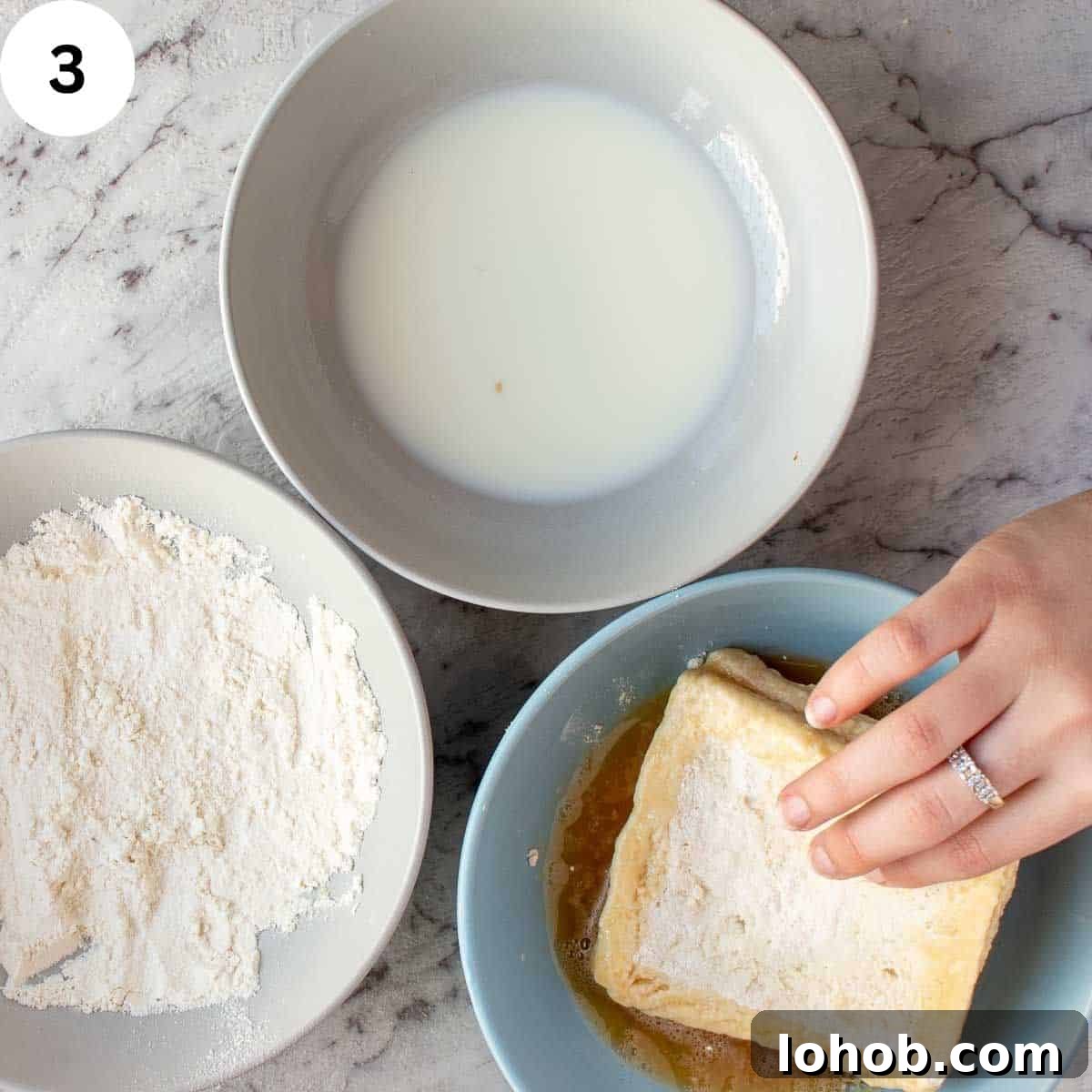 Mozzarella in Carrozza: Crispy Italian Fried Cheese Sandwich Recipe 6 Dipping a sandwich in beaten egg with bowl of milk and bowl of flour on the side.