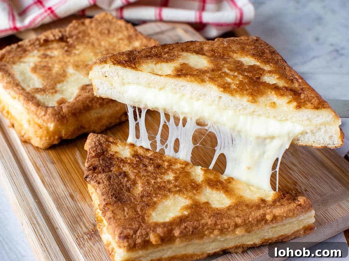 Mozzarella in Carrozza: Crispy Italian Fried Cheese Sandwich Recipe 8 Fried sandwich cut in half and showing cheese pull with second sandwich in background.