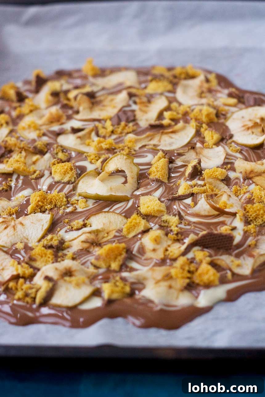 A closeup of toffee apple chocolate bark on baking paper before being cut up into pieces.