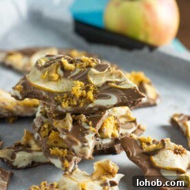 A stack of toffee apple chocolate bark on baking paper with an apple in the background