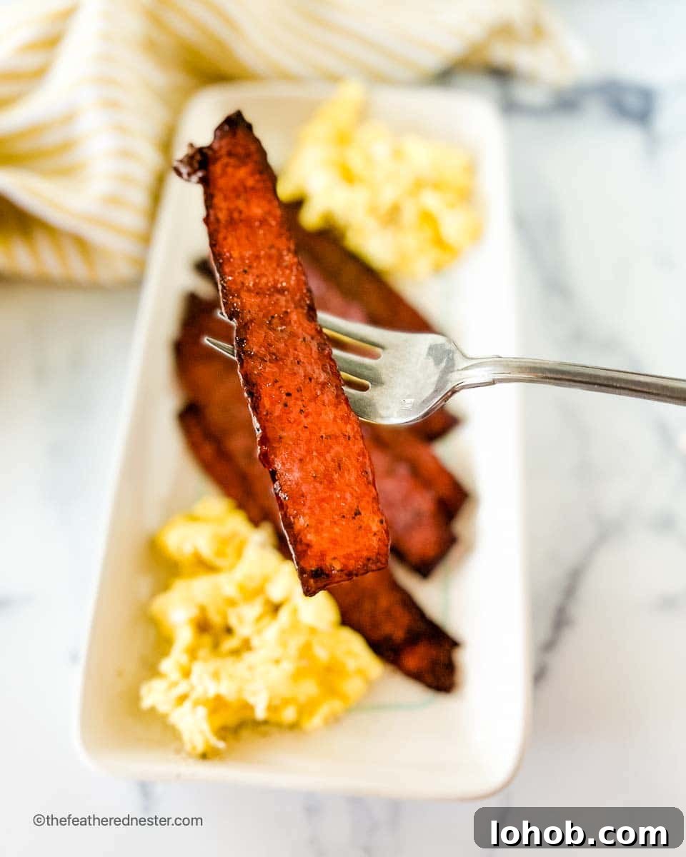 A white platter with oven baked turkey bacon and scrambled eggs.