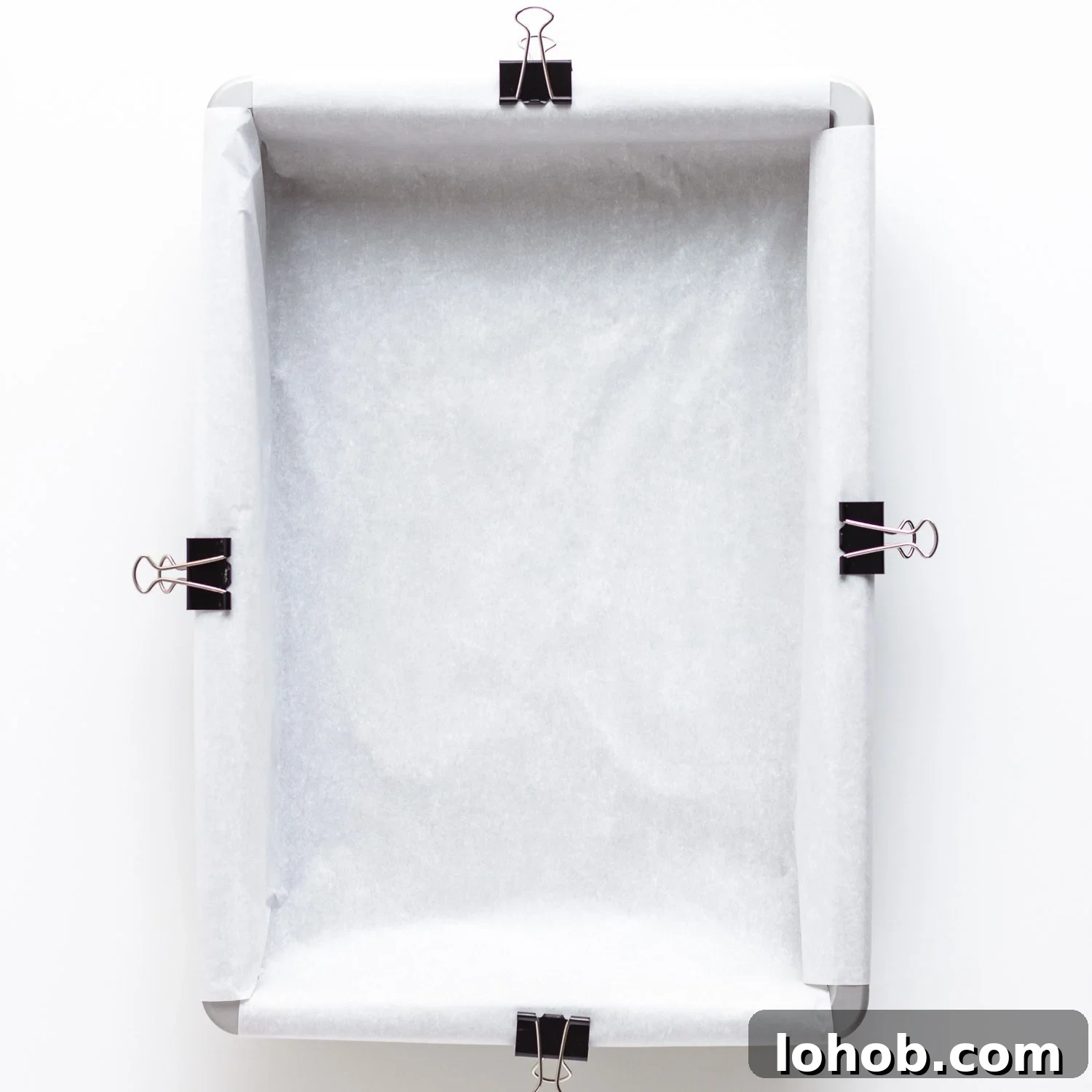 Baking pan lined with parchment paper that binder clips are holding in place.