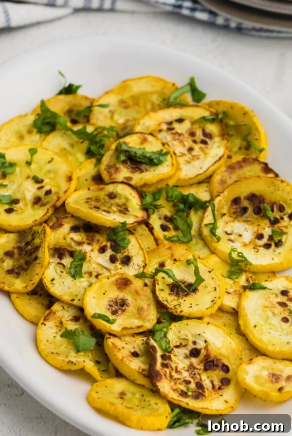 Crispy Air Fryer Green Beans with Garlic and Parmesan 11 Yellow squash cooked in the air fryer on a white plate and ready to serve.