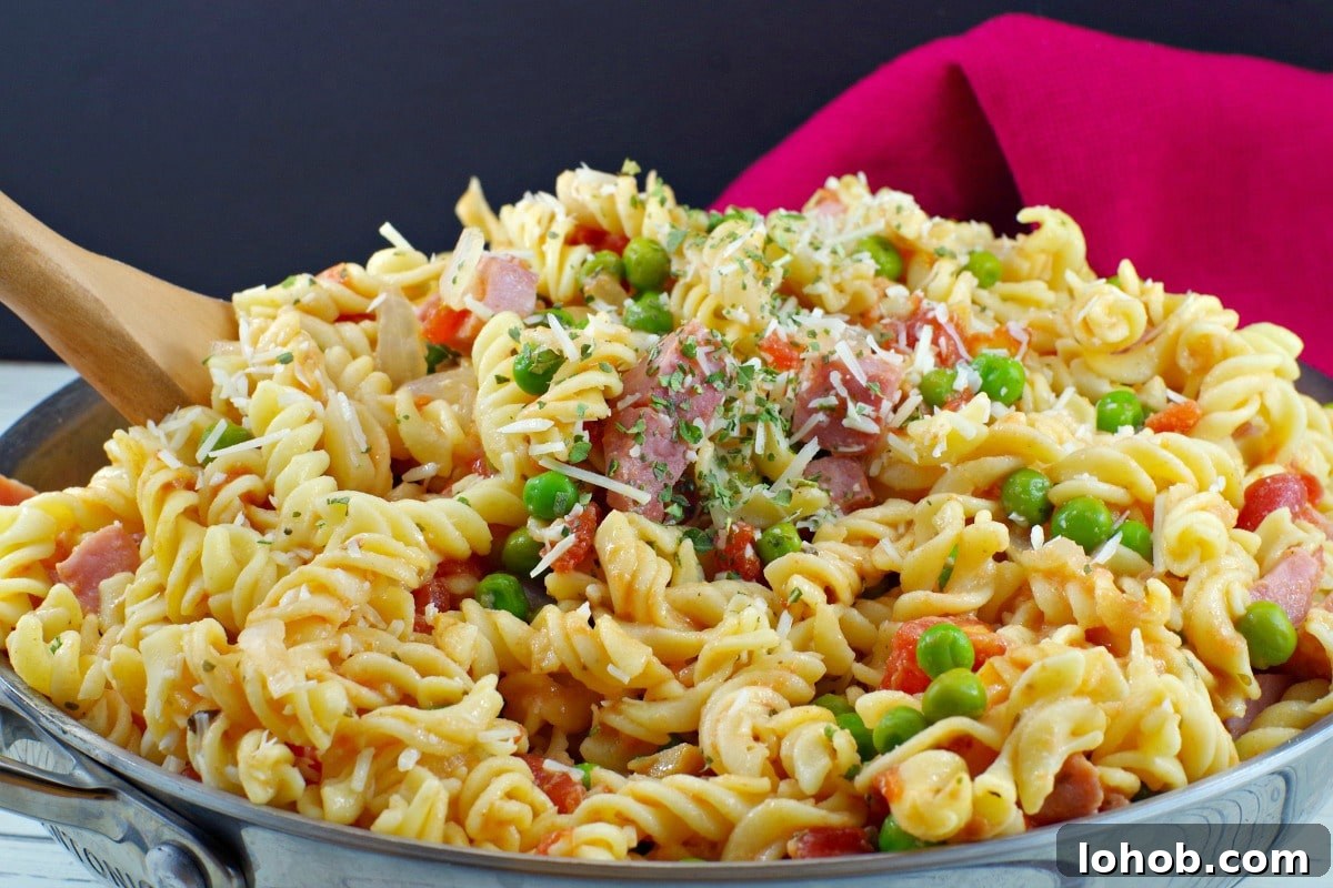 Leftover Ham and Pea Pasta Recipe for Quick Weeknight Meals 2 Healthy Ham Pasta in a skillet with a wooden spoon, with a red napkin in the background.