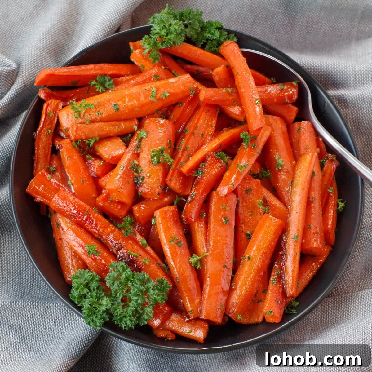 Leftover Ham and Pea Pasta Recipe for Quick Weeknight Meals 11 brown sugar glazed carrots in a black bowl, with a spoon, on grey linen