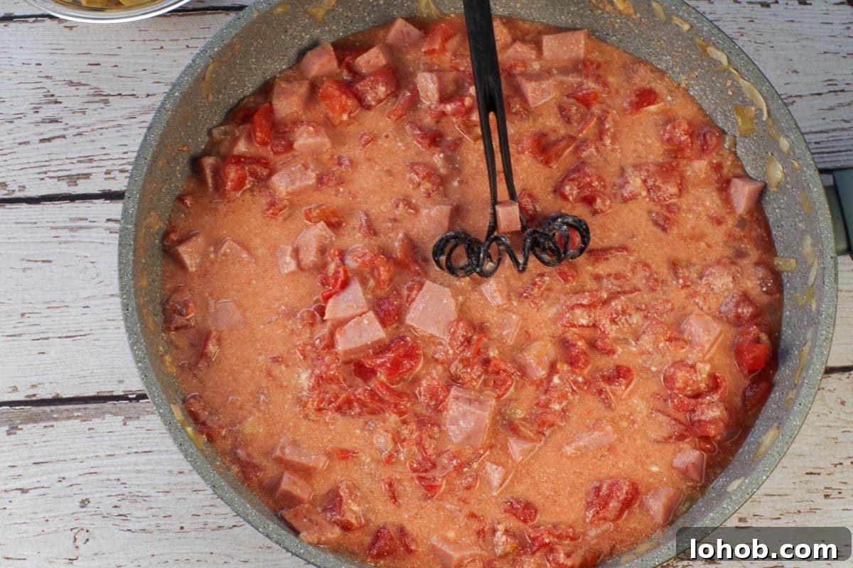 Leftover Ham and Pea Pasta Recipe for Quick Weeknight Meals 7 Mascarpone cheese whisked into ham mixture in large skillet with black whisk