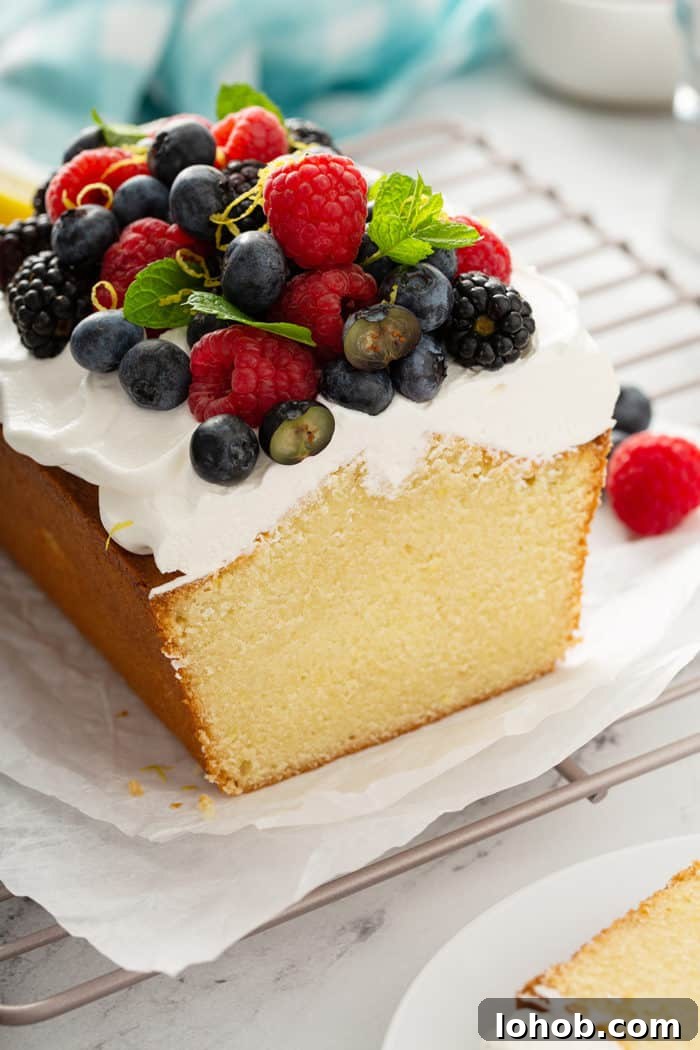 Cross view of sliced lemon whipping cream cake, topped with whipped cream and berries