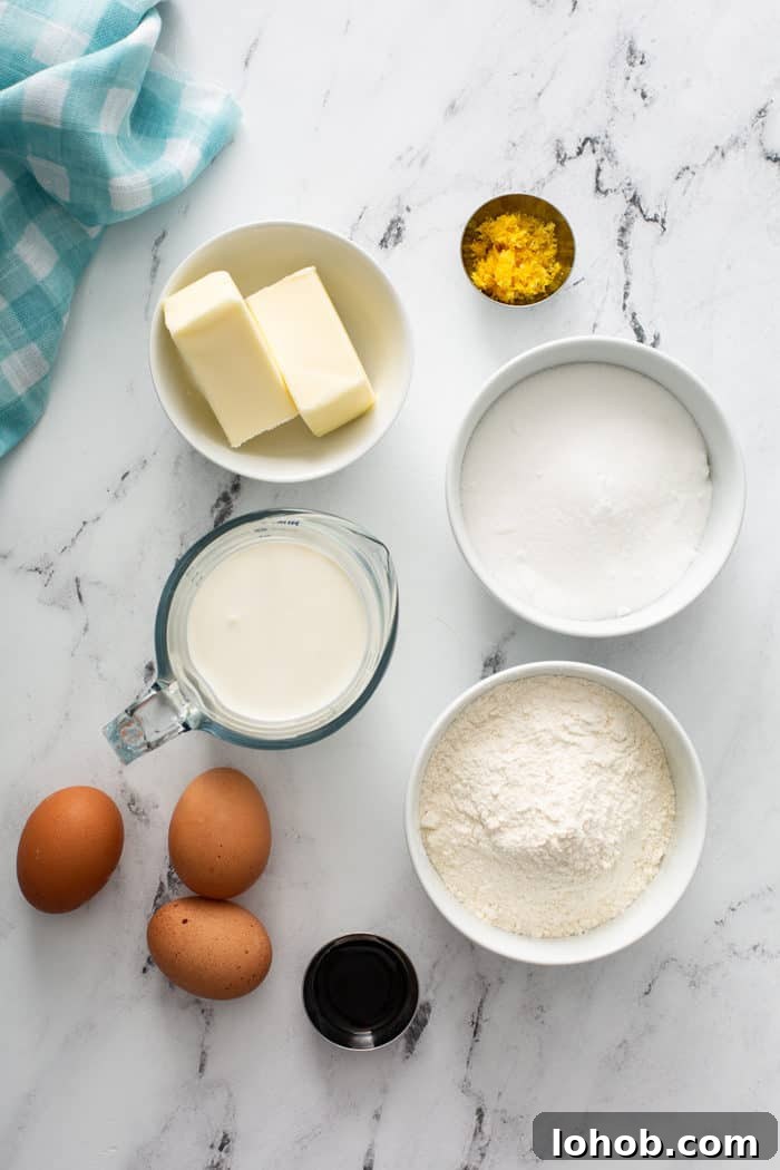 Overhead view of ingredients for lemon whipping cream cake arranged on a marble countertop
