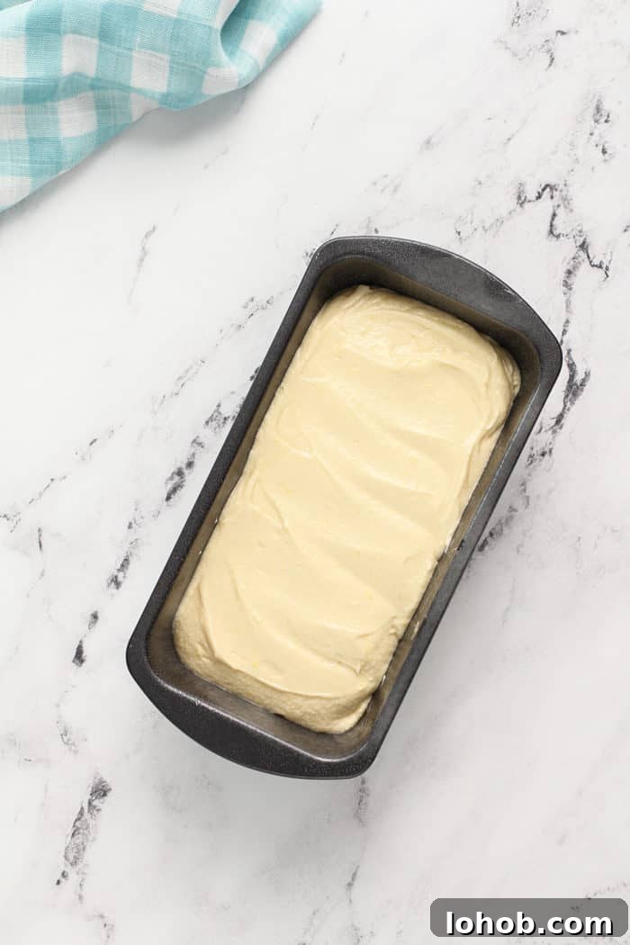 Batter for lemon whipping cream cake in a prepared loaf pan, ready to bake