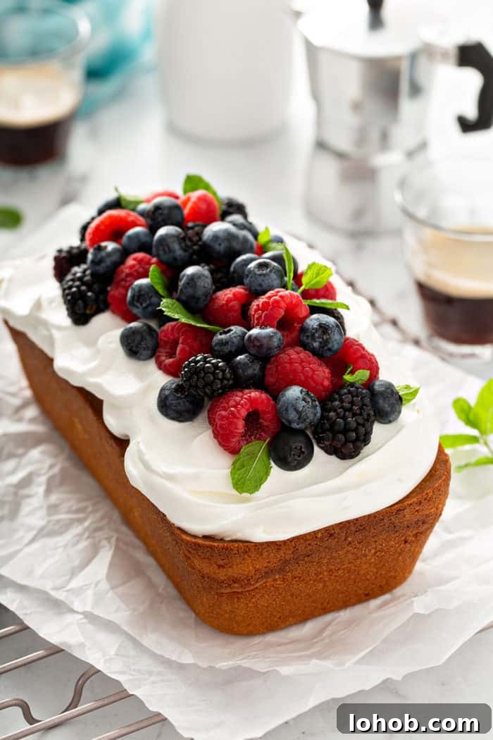 Loaf of lemon whipping cream cake topped with whipped cream and fresh berries
