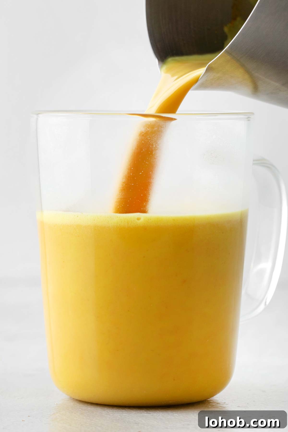 Pouring golden milk in a mug.