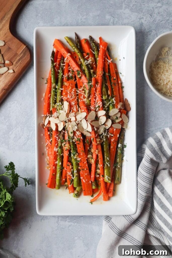 white plate with carrots and asparagus topped with cheese and sliced almonds