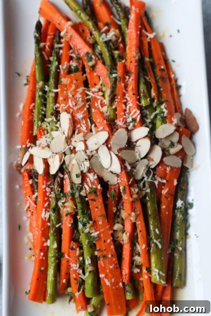 white plate with carrots and asparagus topped with cheese and sliced almonds