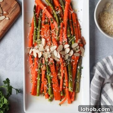 white plate with carrots and asparagus topped with cheese and sliced almonds