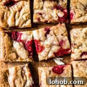 Raspberry White Chocolate Blondies Recipe — Chewy, Fruity Bars 13 Raspberry white chocolate blondies on a wooden cutting board.