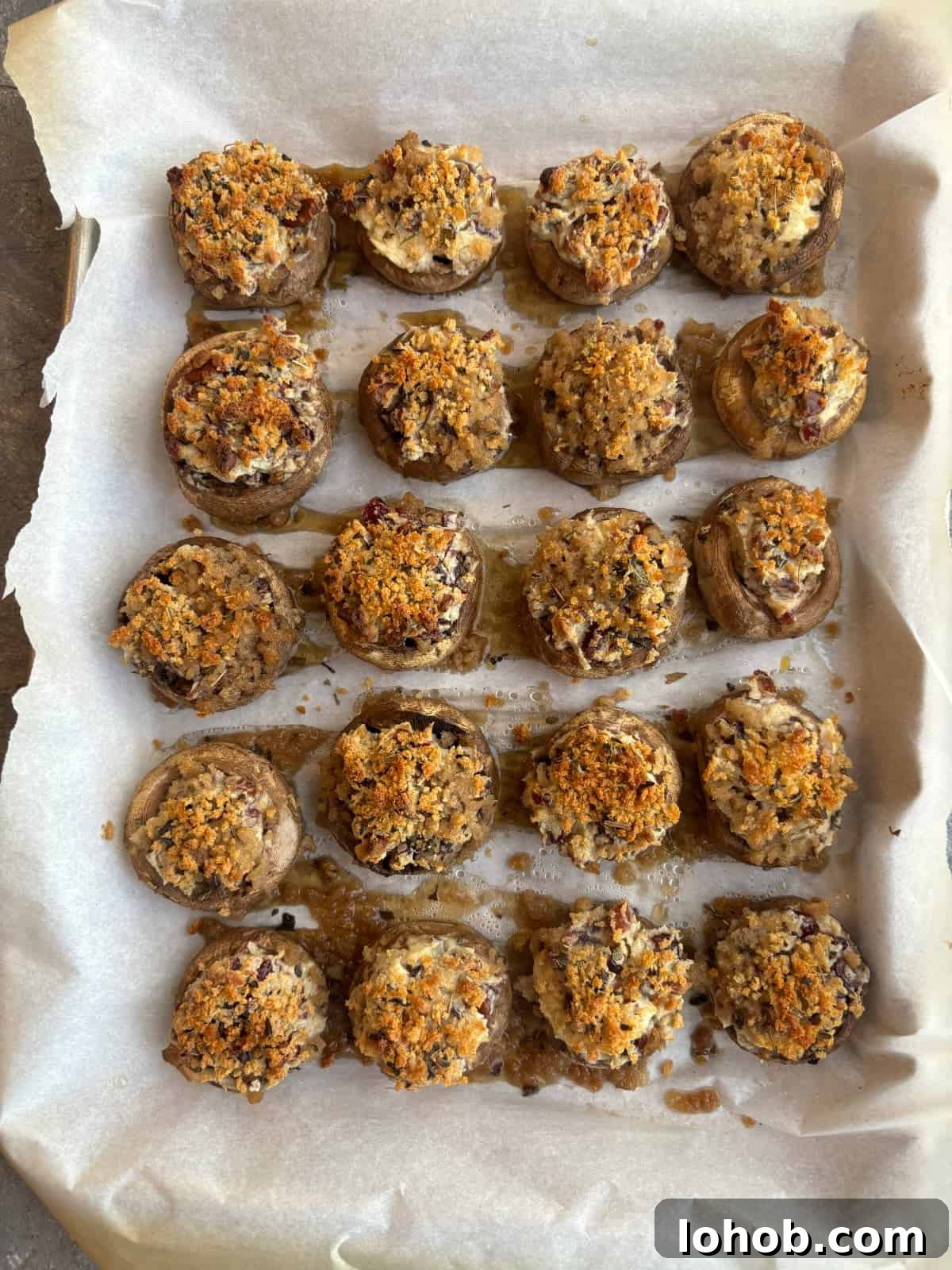 an overhead image of a parchment lined baking sheet topped with stuffed mushrooms after they have been baked in the oven.
