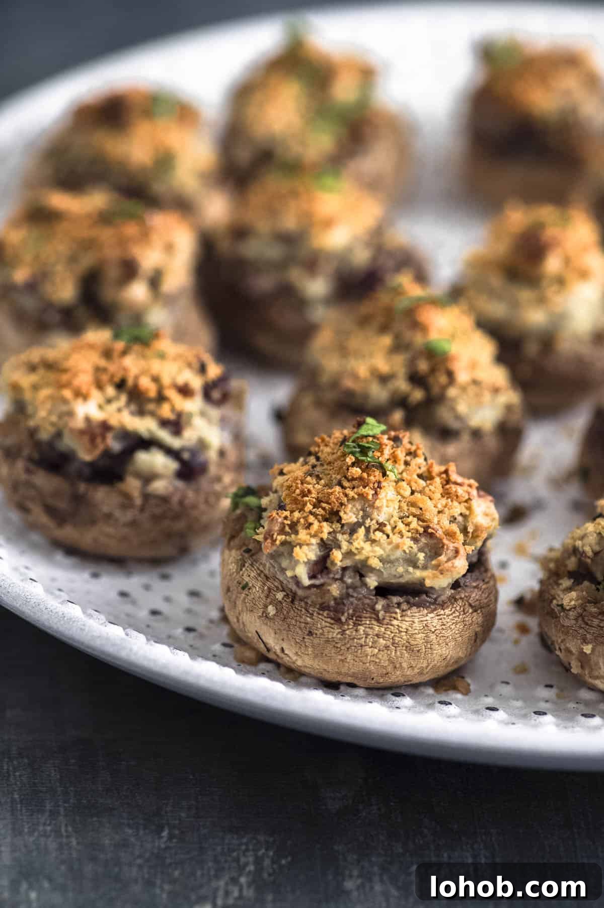 Close up view one stuffed mushrooms with the rest of them blurred in the background