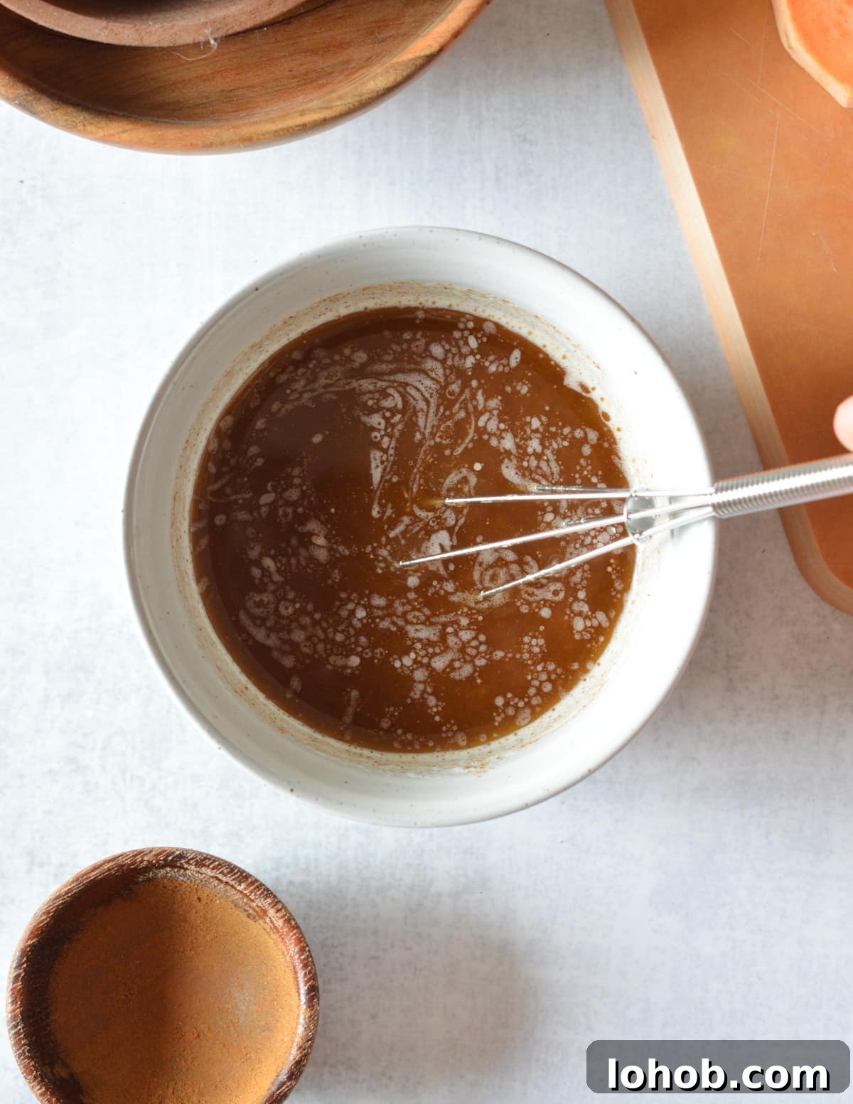 Roasted Sweet Potato Slices with Maple Candied Pecans 7 stirring a bowl of melted butter, maple syrup, and cinnamon with a mini whisk.