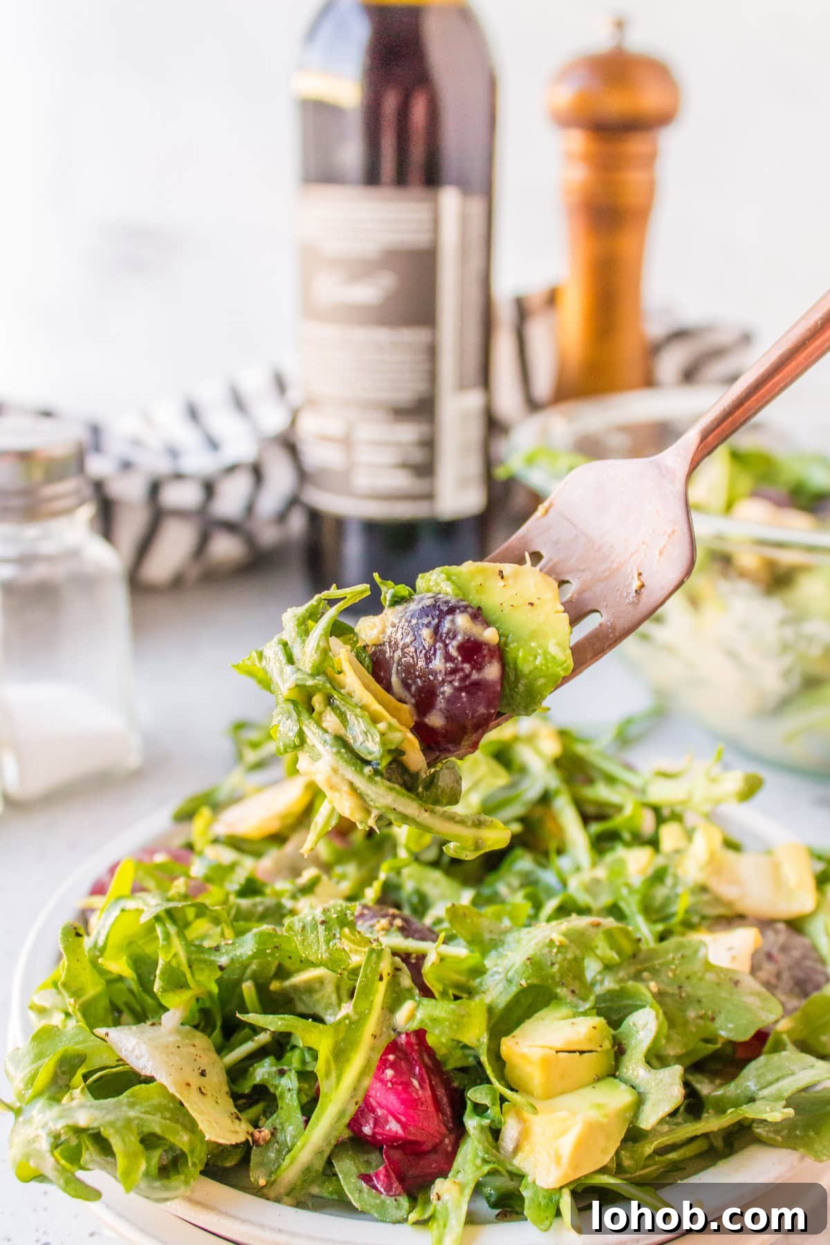 grape avocado and arugula salad with fork full of salad