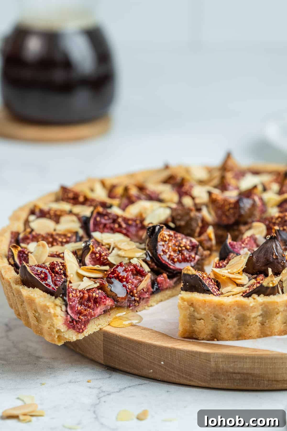 Sliced fig tart on a wooden board lined with parchment.