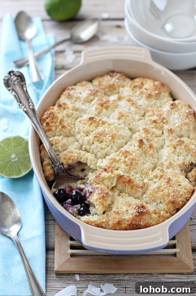 A purple baking dish filled with Blueberry Lime Coconut Cobbler.