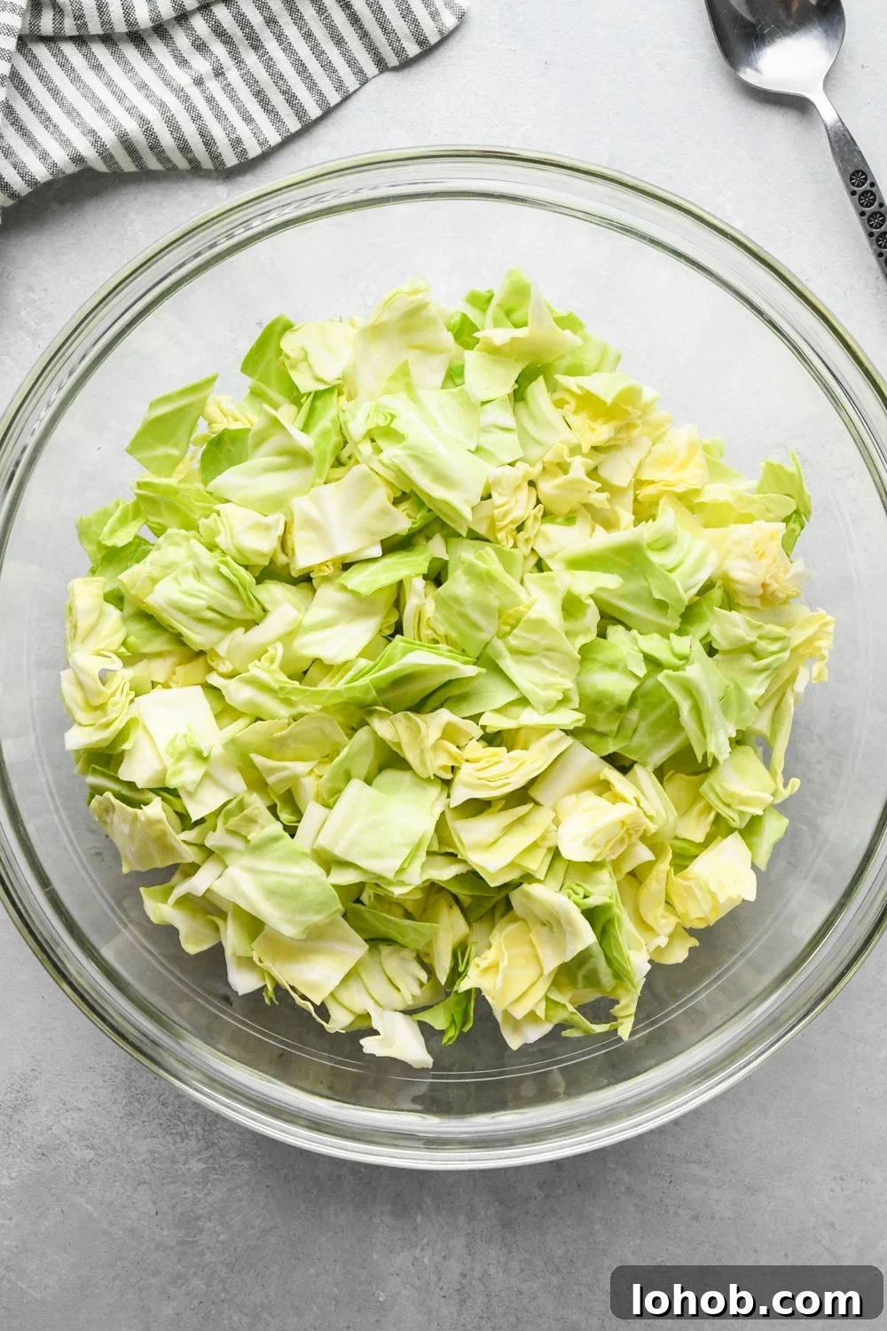 How to make chopped green cabbage salad: Chopped green cabbage in a large glass bowl. 