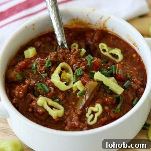Texas-Style Crock Pot Chili Recipe (No Beans) 7 Square image closeup of finished chili served in a white bowl and garnished with pepperoncini.