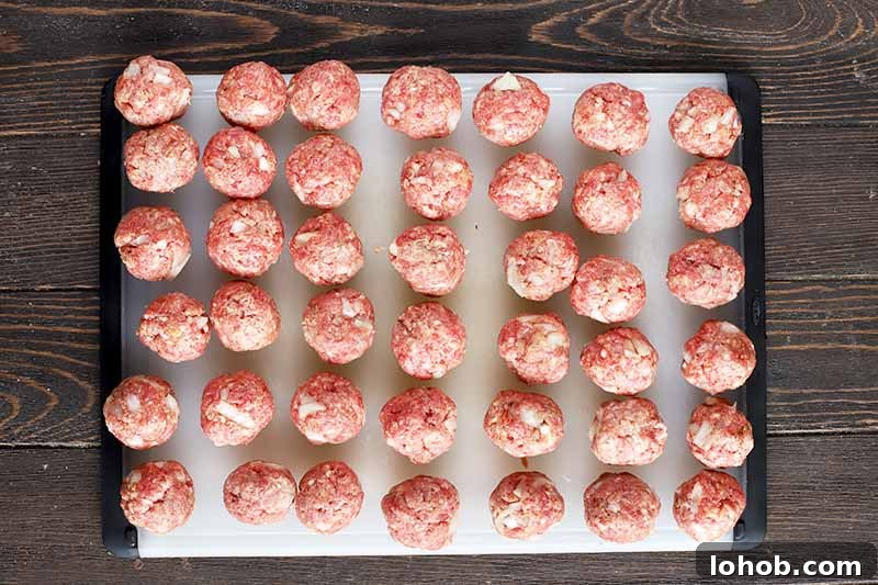 Sweet and Tangy Classic Meatballs Recipe for Weeknight Dinners 9 Horizontal image of raw ground beef formed in balls on a cutting board.
