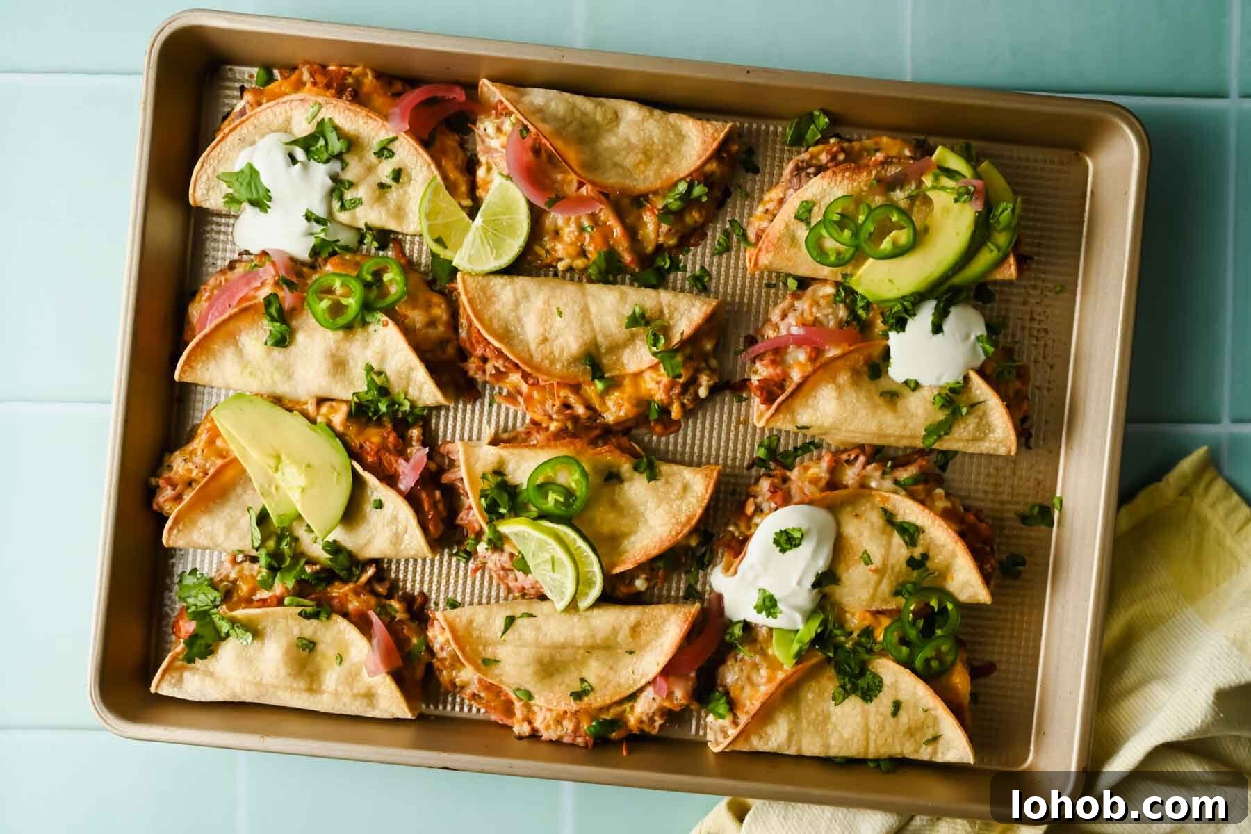 baked crispy pork tacos topped with herbs, lime wedges, avocado and sour cream.