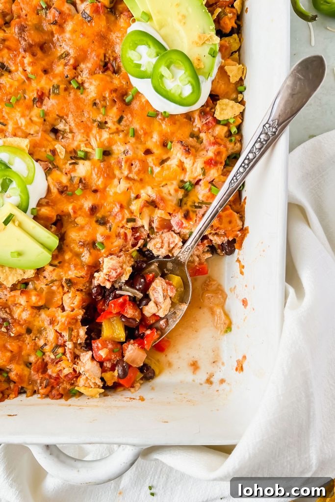 baked chicken taco casserole garnished with sour cream, jalapeño slices, and avocado slices.
